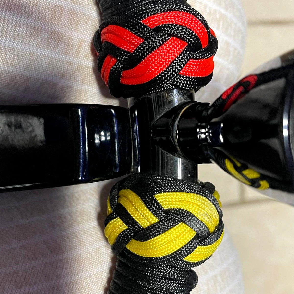 Detalle del tejido paracord a mano - nudos rojos y amarillos sobre negro