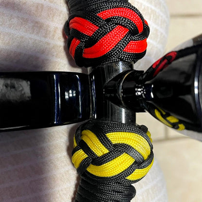 Detalle del tejido paracord a mano - nudos rojos y amarillos sobre negro
